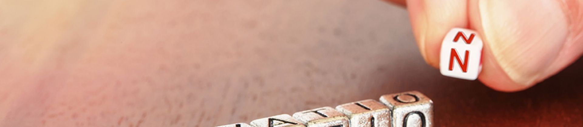 des cubes de lettres alignés pour écrire INNOVATIO et deux doigts qui viennent ajouter le N final